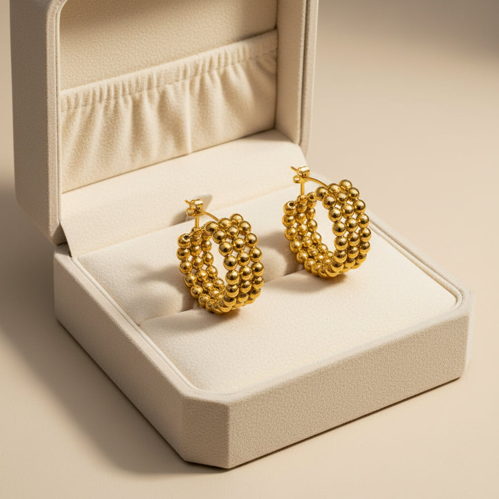 Pair of gold hoop earrings with bead-like design on a white background
