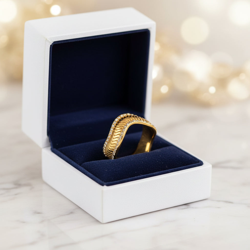 A gold wavy band ring decorated with small clear crystals along the front edge, shown on a clean white background.