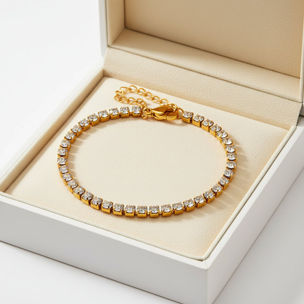 A gold tennis bracelet with clear round-cut stones, featuring a lobster clasp and an adjustable chain extender, shown on a plain white background.