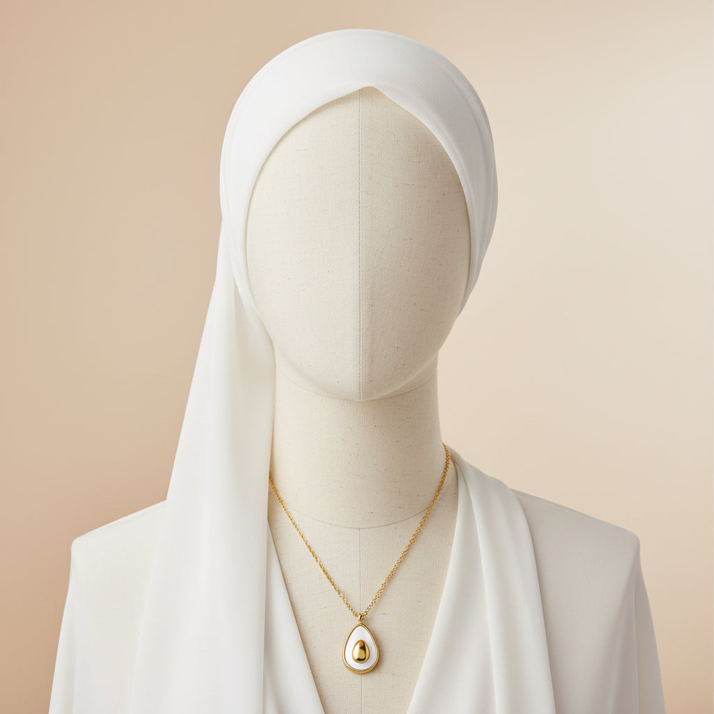 Gold necklace with a teardrop-shaped pendant on a white background
