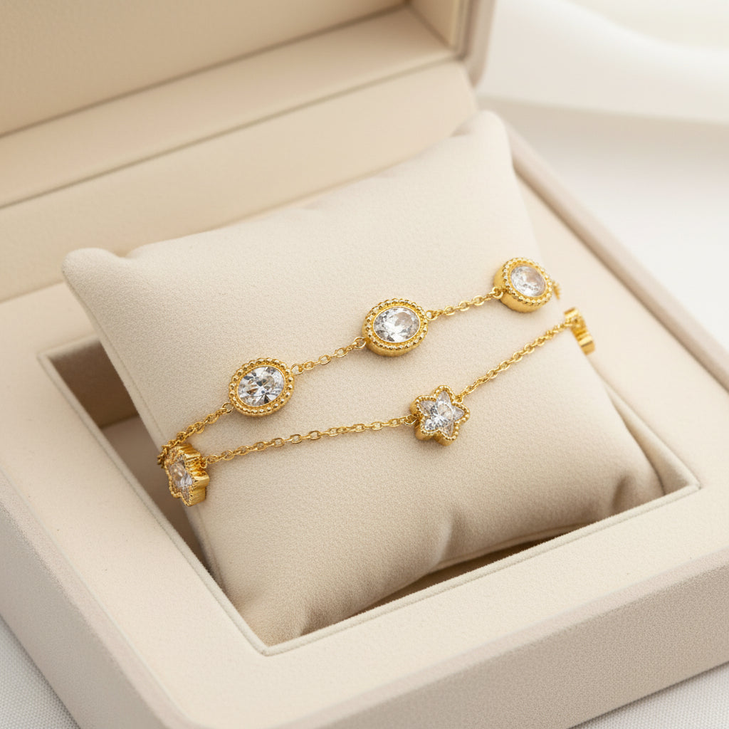 A gold-tone double-strand chain bracelet with five oval clear crystal settings and two flower-shaped crystal settings, displayed on a clean white background.